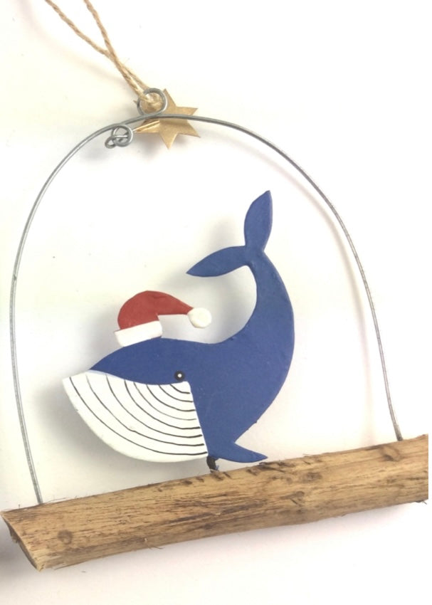 Blue whale in santa hat on wooden stand with metal arch and gold star 